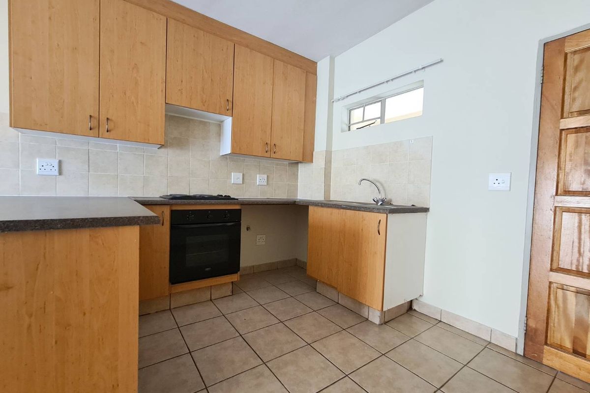 A functional kitchen featuring light wood laminate cabinetry, built-in oven, gas hob, tiled backsplash, and tiled flooring, offering a clean and practical workspace.
