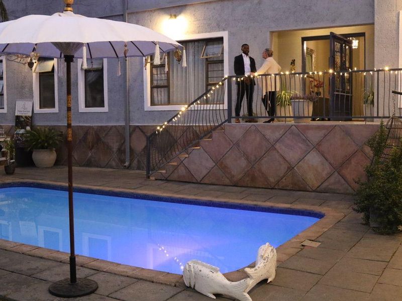 Outdoor pool area featuring a tiled patio, stone stairs with wrought iron railings, and exterior lighting, providing a pleasant space for relaxation.