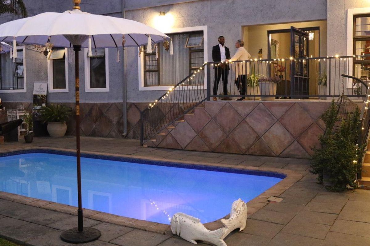 Outdoor pool area featuring a tiled patio, stone stairs with wrought iron railings, and exterior lighting, providing a pleasant space for relaxation.
