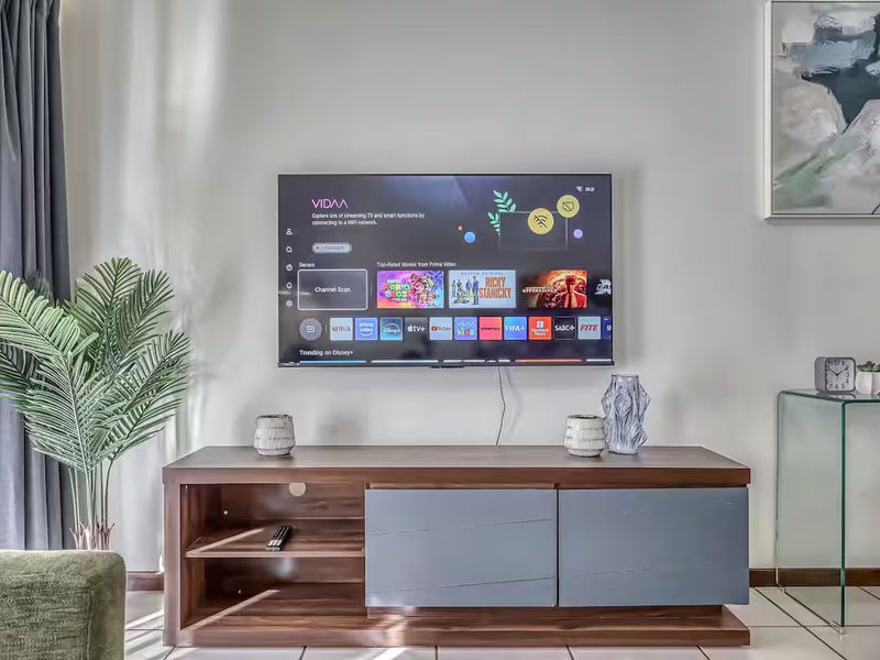 A well-maintained living room area featuring tiled flooring and a wall-mounted television setup.