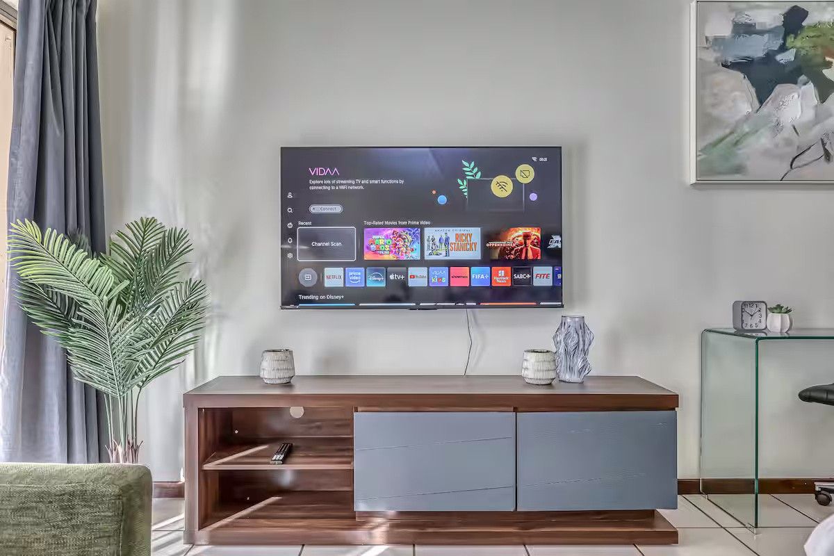 A well-maintained living room area featuring tiled flooring and a wall-mounted television setup.