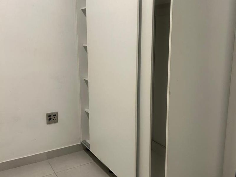 A bedroom featuring a white built-in sliding door wardrobe and neutral tiled flooring.