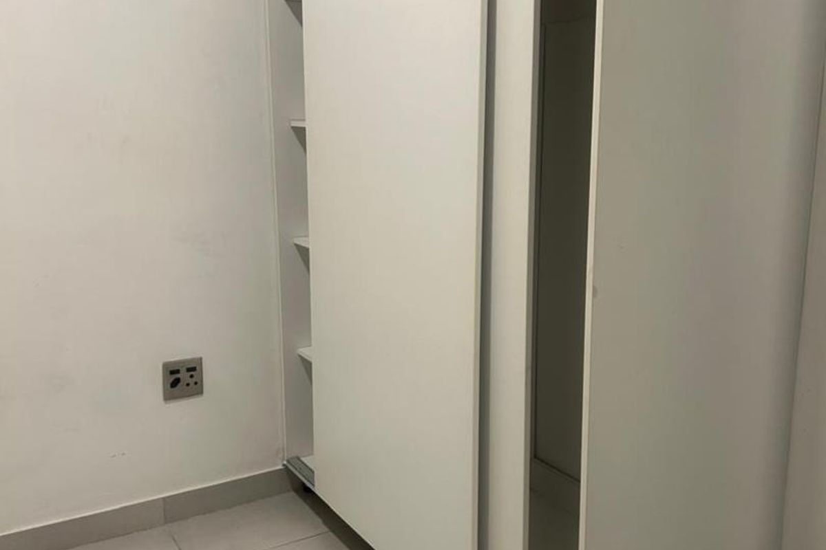 A bedroom featuring a white built-in sliding door wardrobe and neutral tiled flooring.