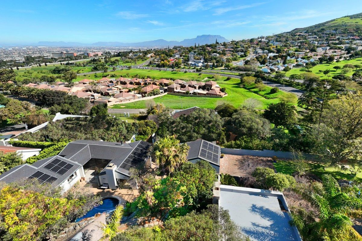 Aerial view of the property showcasing the roof structure, solar panels, swimming pool, and surrounding residential landscape with mountain views.