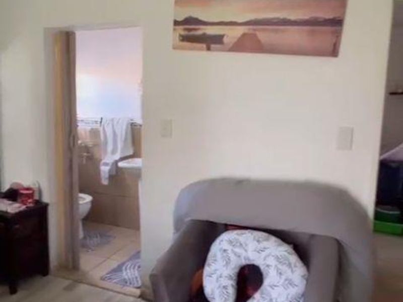 A bedroom interior featuring light-toned laminate flooring and a doorway leading to an adjacent bathroom area.