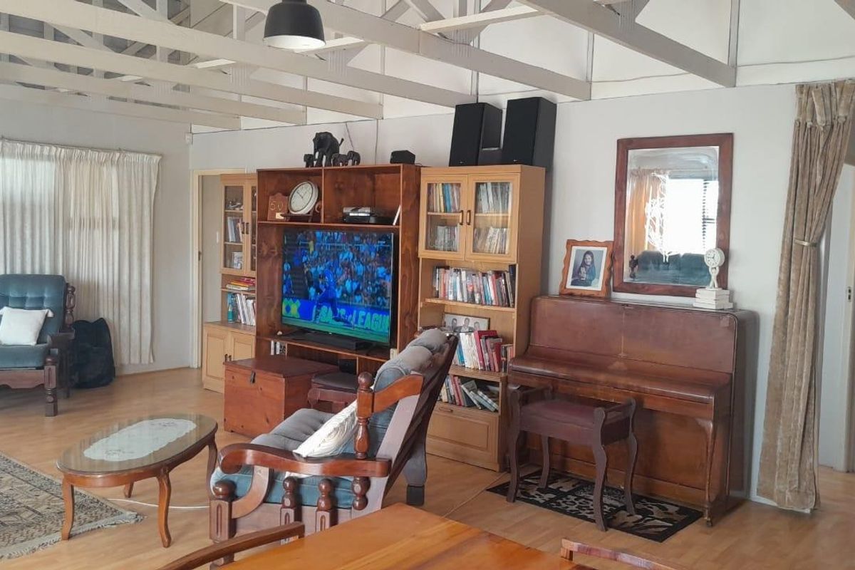 Spacious living area featuring exposed timber roof trusses, laminate flooring, and neutral wall finishes, providing a comfortable and versatile family space.