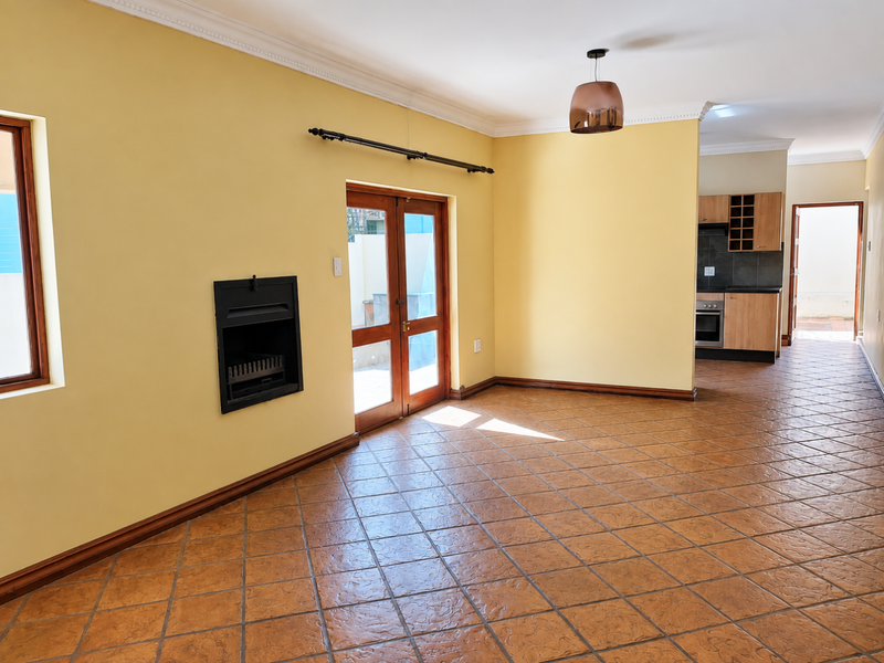 Spacious open-plan living area featuring terracotta floor tiles, a built-in fireplace, and a seamless transition to the adjacent kitchen space.