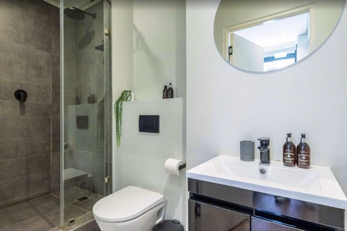 Modern bathroom featuring a glass-enclosed walk-in shower, wall-mounted toilet, and a sleek vanity with a contemporary basin.