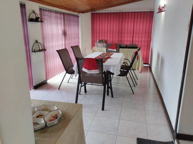 A covered patio area featuring tiled flooring, timber ceiling, and vertical blinds, suitable for outdoor dining and entertainment.