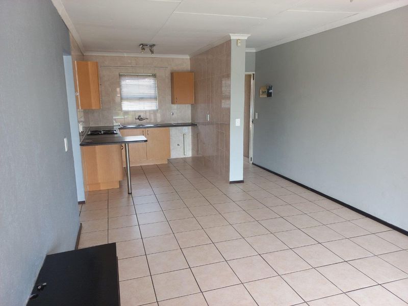 Open plan living and kitchen area featuring tiled flooring, built-in cabinetry, and a functional kitchen layout with a breakfast counter.