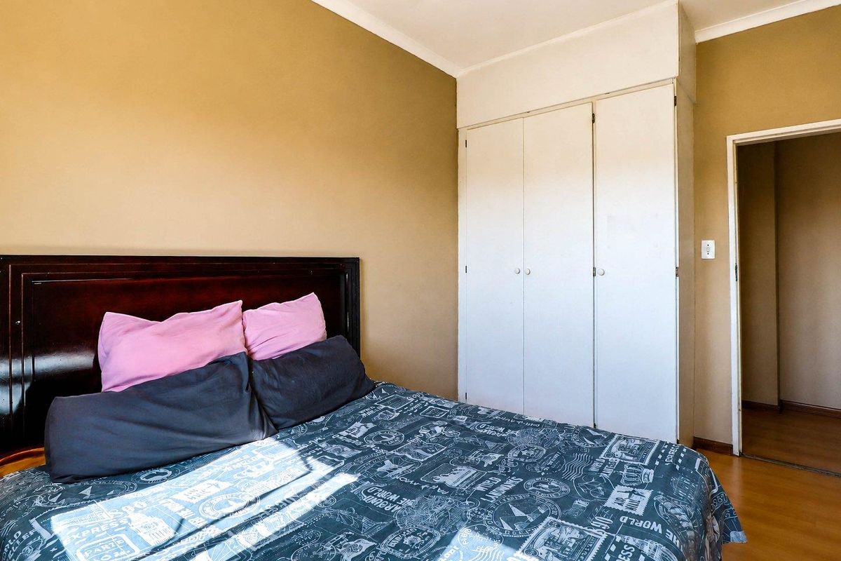 A bedroom featuring laminate flooring, neutral wall paint, and a built-in wardrobe with overhead storage.