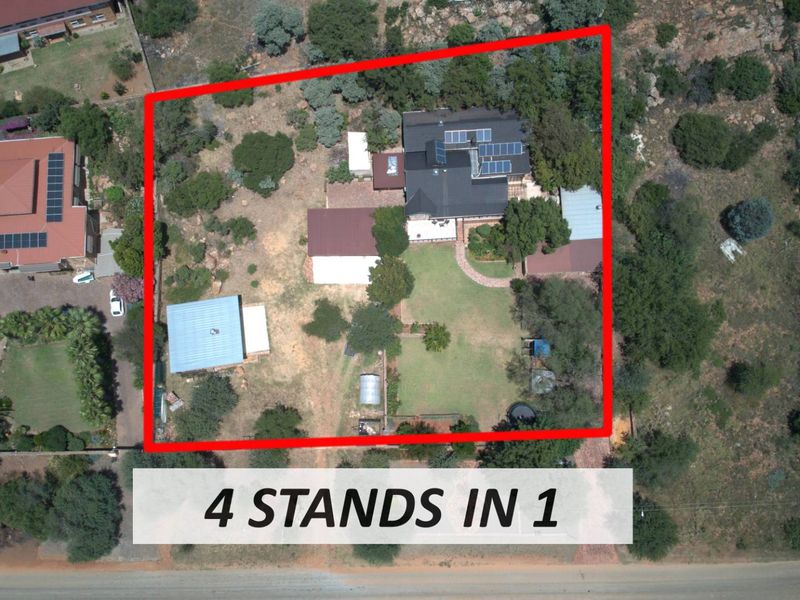 Aerial view of a large residential property featuring multiple structures, solar panel installations, and expansive landscaped grounds.