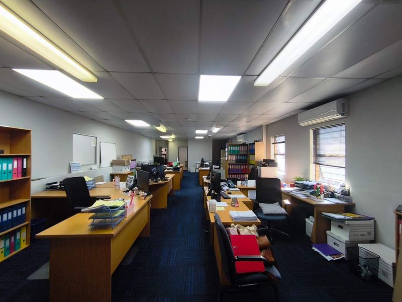 A functional open-plan office space featuring suspended ceilings, integrated fluorescent lighting, split-system air conditioning, and durable carpet tile flooring.