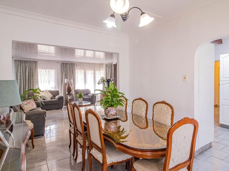 Open plan dining and living area featuring tiled flooring, neutral walls, and an arched transition to the kitchen space.