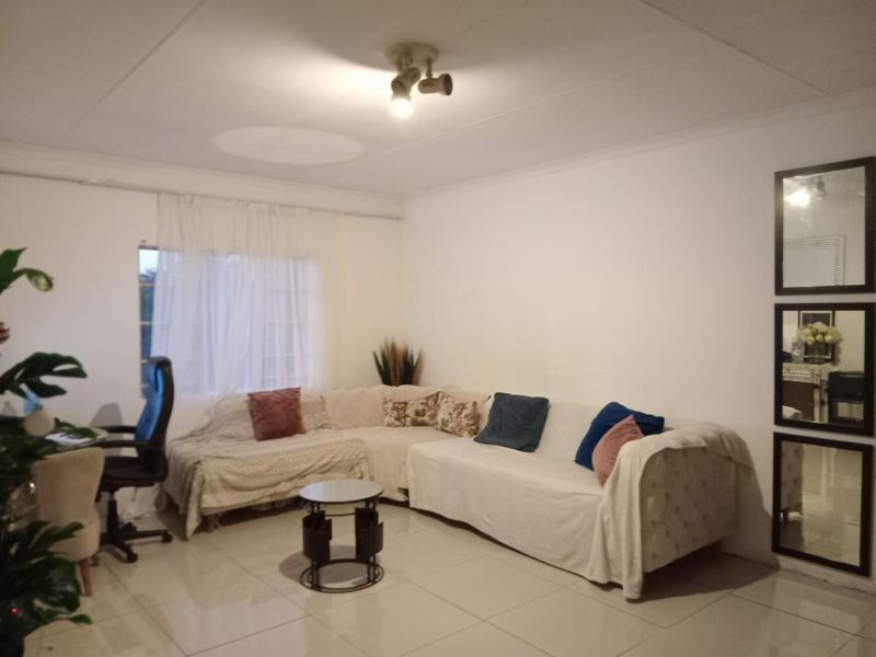 A bright living room featuring neutral tiled flooring and a central ceiling light fixture, providing a clean and functional space.