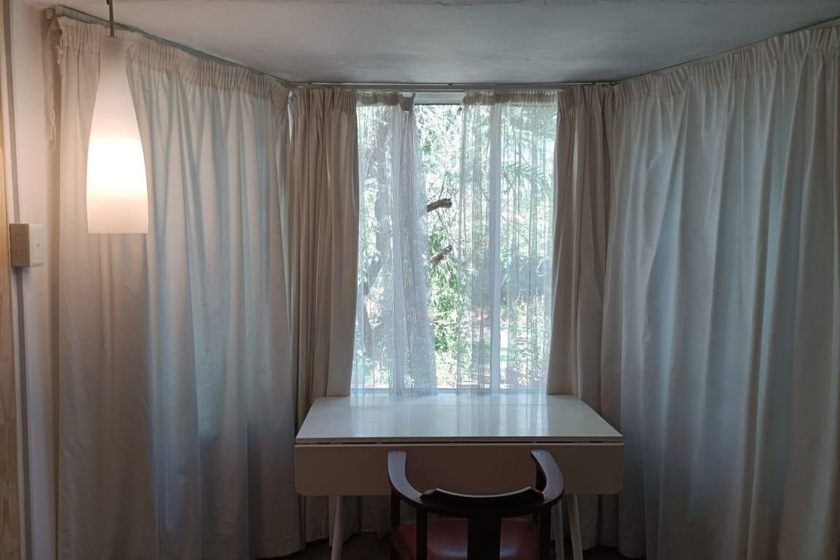 A bedroom area featuring a large window with floor-to-ceiling curtains and a pendant light fixture.