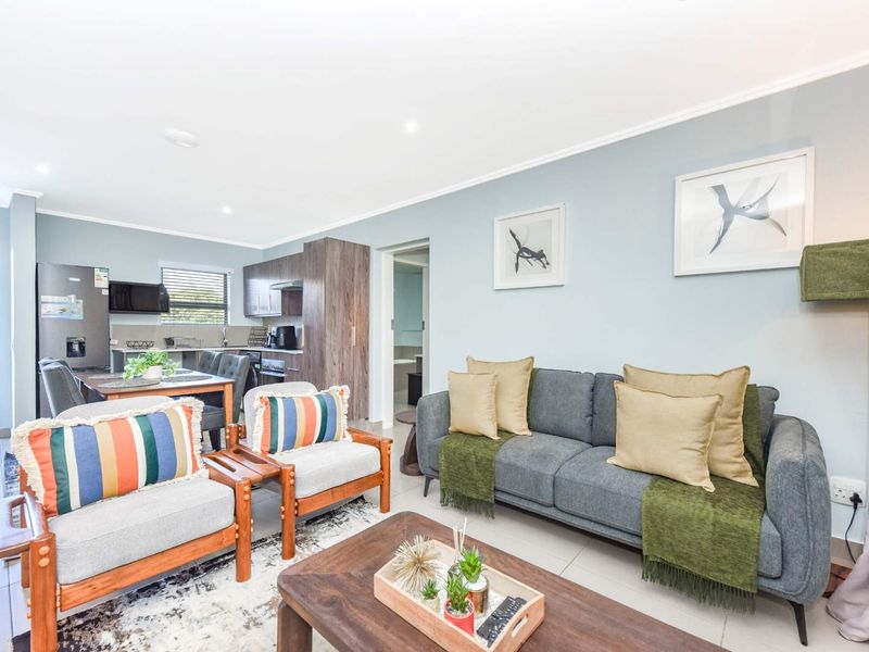 An open-plan living and kitchen area featuring modern cabinetry, tiled flooring, and recessed lighting, creating a bright and functional space.