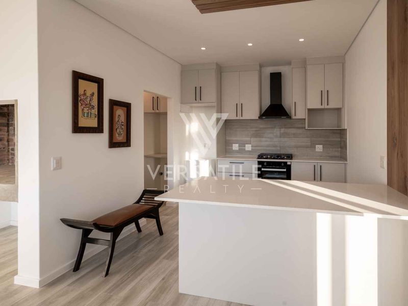 Modern kitchen featuring sleek cabinetry, stone countertops, a gas hob with extractor fan, and recessed lighting, offering a clean and functional culinary space.