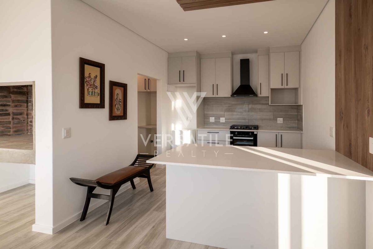 Modern kitchen featuring sleek cabinetry, stone countertops, a gas hob with extractor fan, and recessed lighting, offering a clean and functional culinary space.