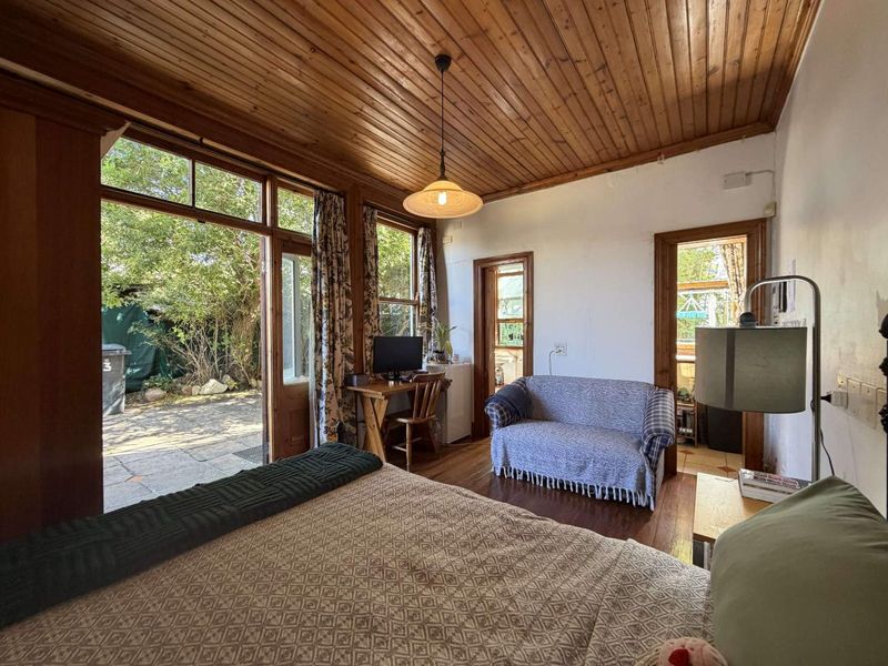 Spacious bedroom featuring warm timber tongue and groove ceilings, hardwood flooring, and direct access to an outdoor patio area through timber-framed doors.