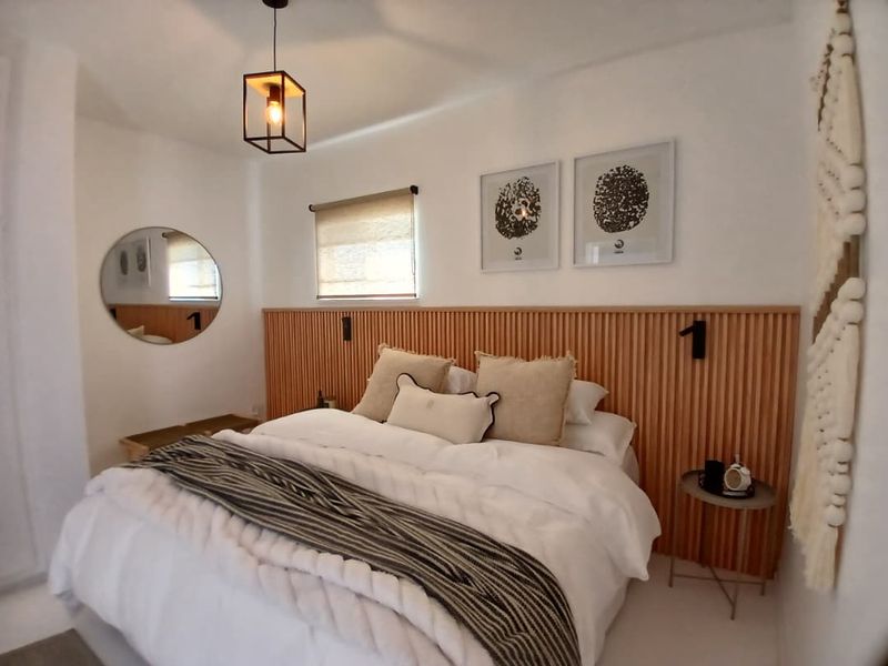 A well-presented bedroom featuring a modern timber slat headboard, neutral decor, and a contemporary pendant light fixture.
