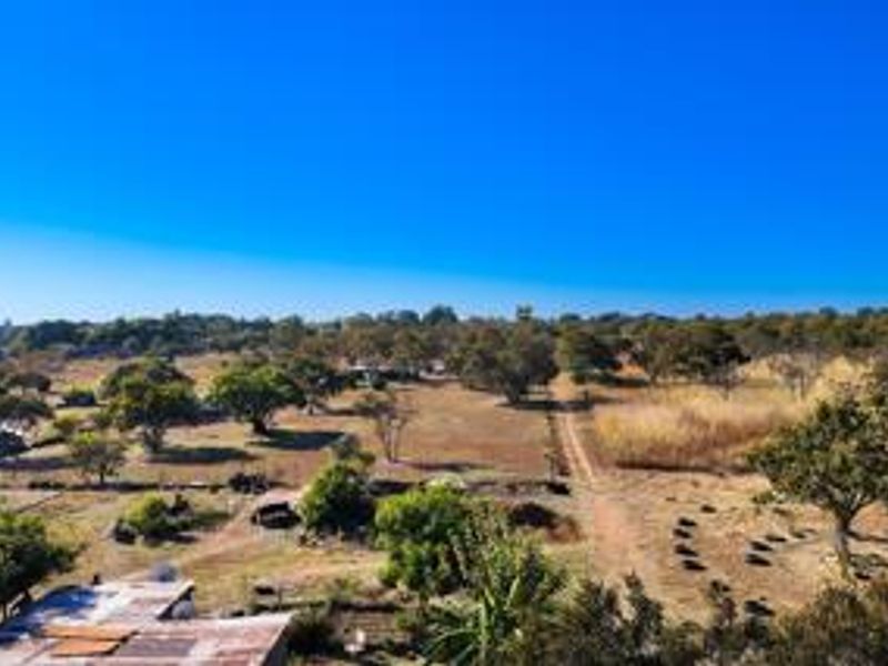 An aerial view of the small holding property, showcasing the expansive landscape, mature trees, and dirt access road.