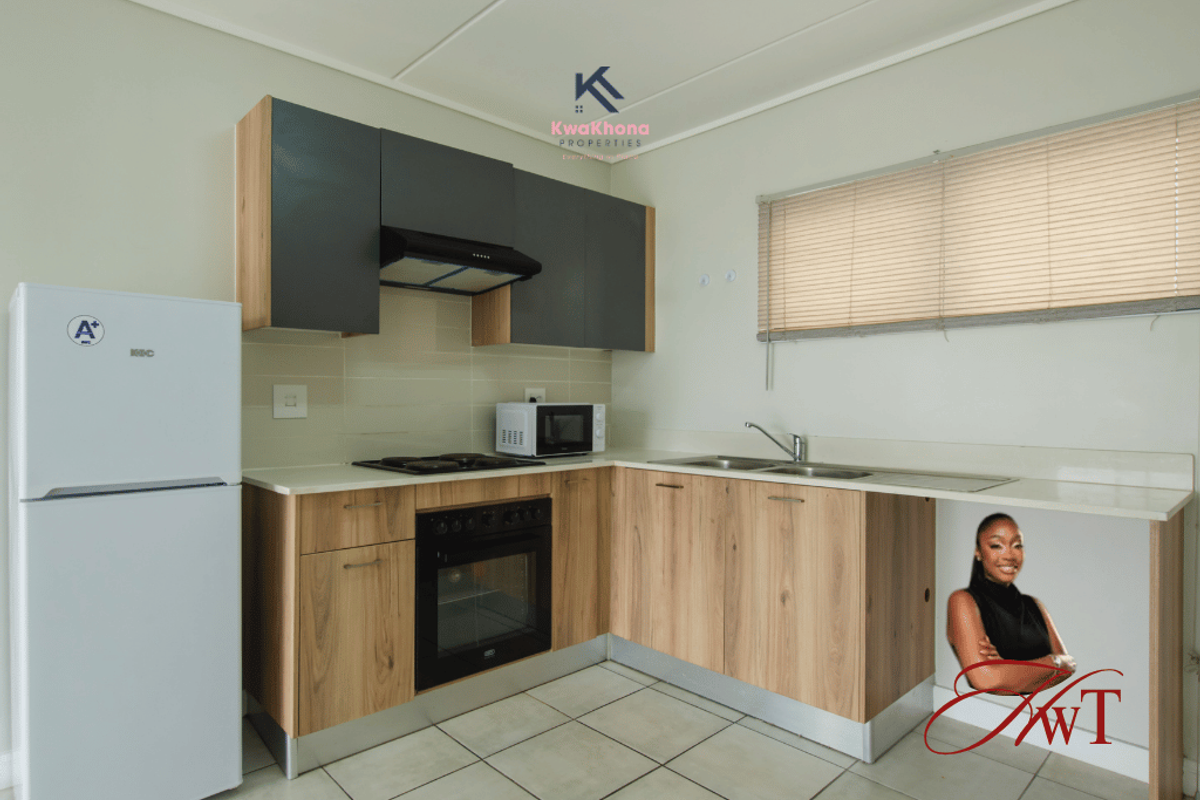 Modern kitchen featuring wood-finish cabinetry, integrated oven and hob, stainless steel sink, and neutral tiled flooring with ample counter space.