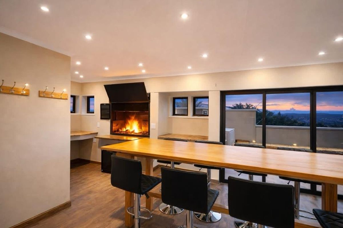 An inviting entertainment area featuring a built-in braai, recessed lighting, and large sliding doors opening to a scenic balcony view.