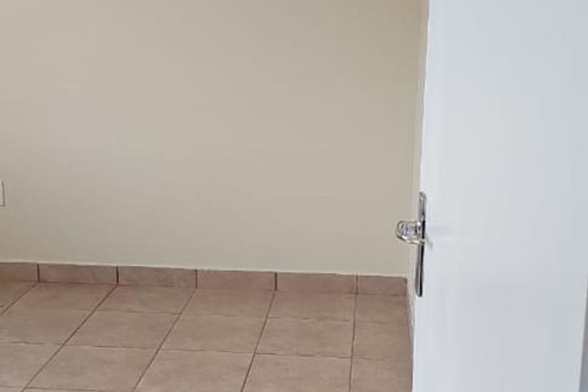 A clean, empty bedroom featuring neutral wall paint and tiled flooring, providing a blank canvas for personalization.