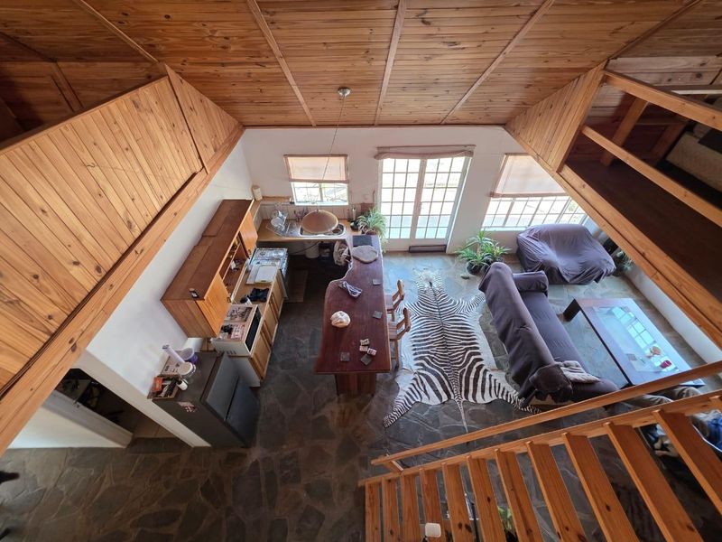 Open-plan living and kitchen area featuring rustic stone flooring, timber vaulted ceilings, and direct access to the outdoors through French doors.