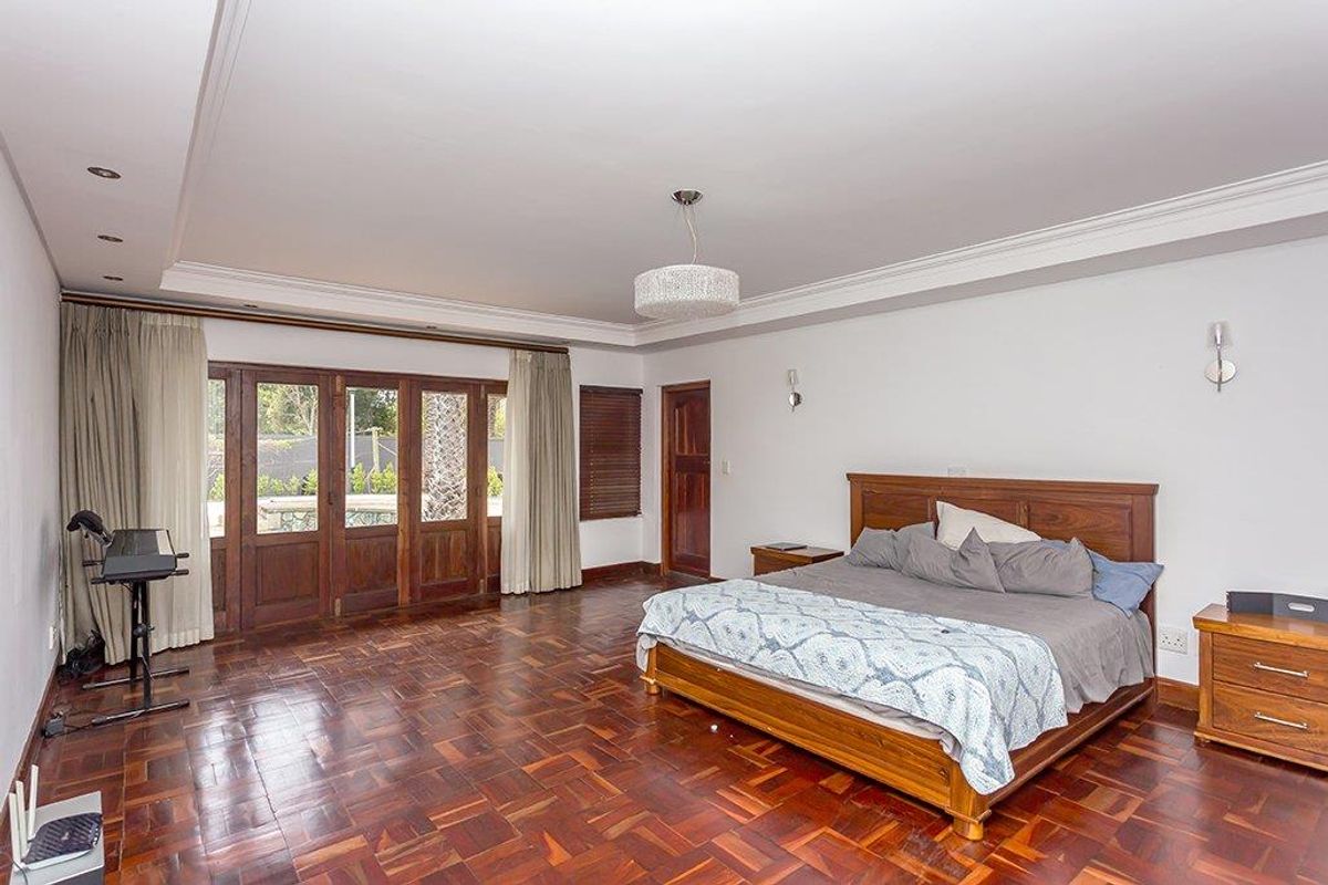 Spacious bedroom featuring classic parquet flooring, coved ceilings, and timber-framed glass doors providing access to the exterior.