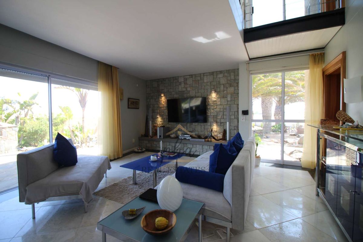 Spacious living room featuring a stone-clad feature wall, tiled flooring, and large sliding glass doors providing ample natural light and garden access.