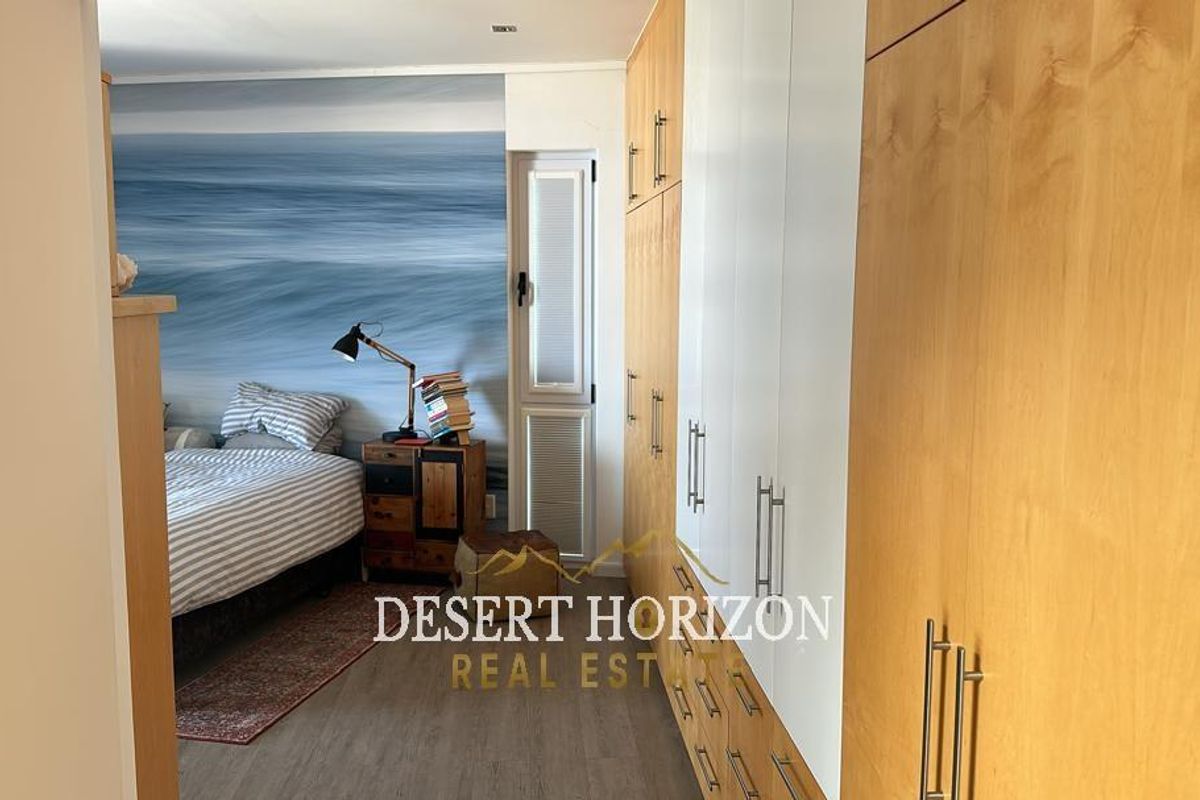 A well-maintained bedroom featuring extensive built-in wooden cabinetry and a feature wall with a coastal-themed mural.