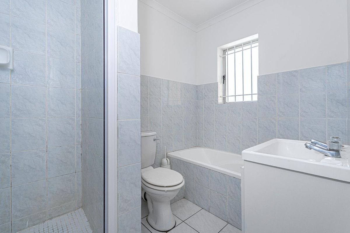 A functional bathroom featuring a built-in bathtub, separate shower enclosure, toilet, and vanity basin with tiled walls and flooring.