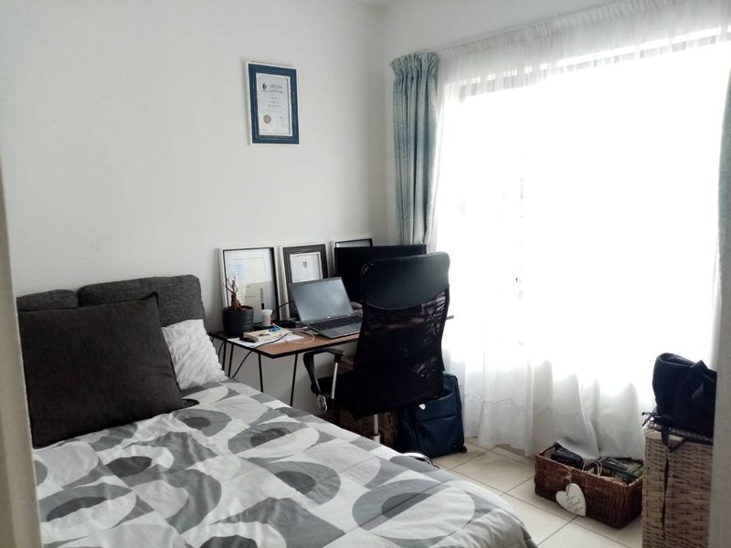 A functional bedroom featuring tiled flooring and a large window that allows for ample natural light.