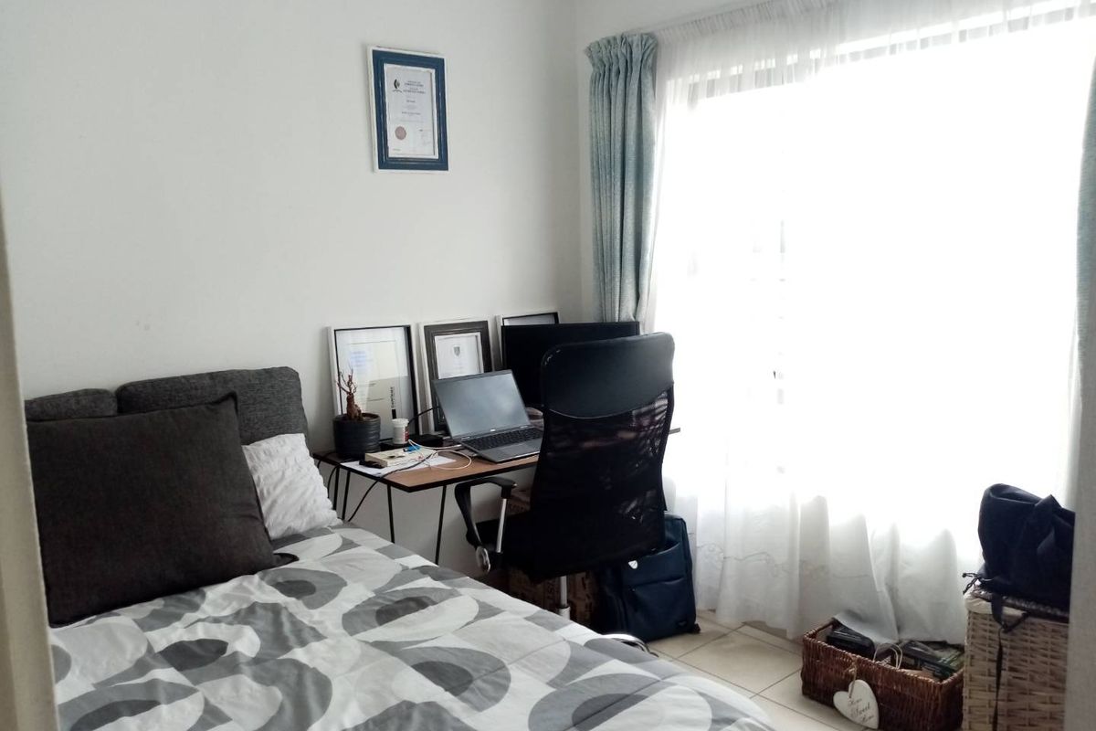 A functional bedroom featuring tiled flooring and a large window that allows for ample natural light.