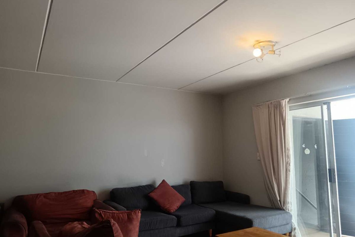 A living room featuring tiled flooring and a sliding glass door providing access to an outdoor area.