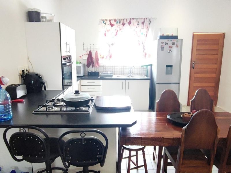Open-plan kitchen and dining area featuring built-in cabinetry, a gas hob, built-in oven, and tiled flooring, providing a functional space for cooking and dining.