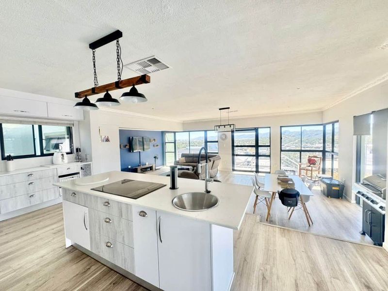 Spacious open-plan living area featuring a modern kitchen island with integrated cooktop, sleek cabinetry, and expansive windows offering panoramic views.