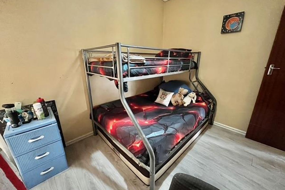 A functional bedroom featuring light-toned laminate flooring and a standard interior door.