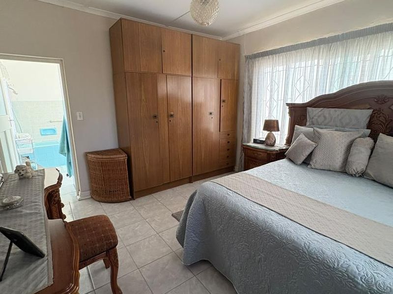 A bedroom featuring tiled flooring, a built-in wooden wardrobe, and an en-suite bathroom access.