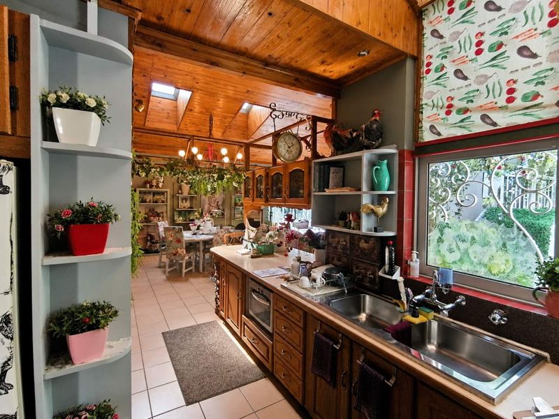 Open-plan kitchen and dining area featuring a timber-clad vaulted ceiling, skylights, and traditional wooden cabinetry with integrated appliances.