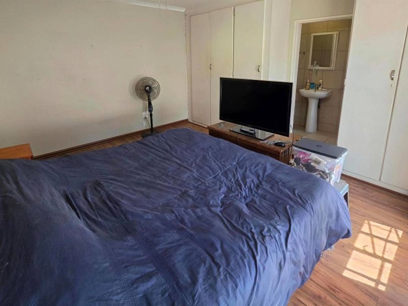 A bedroom featuring laminate flooring, built-in cupboards, and direct access to an en-suite bathroom.