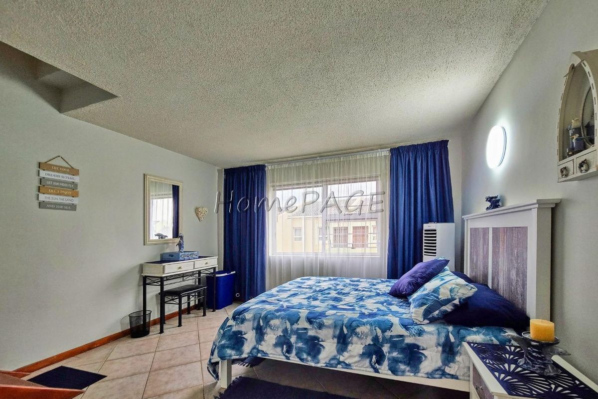 A bedroom featuring tiled flooring, a large window with curtains, and a textured ceiling finish.