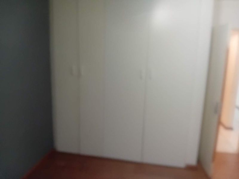 A bedroom featuring built-in cupboards and laminate flooring.