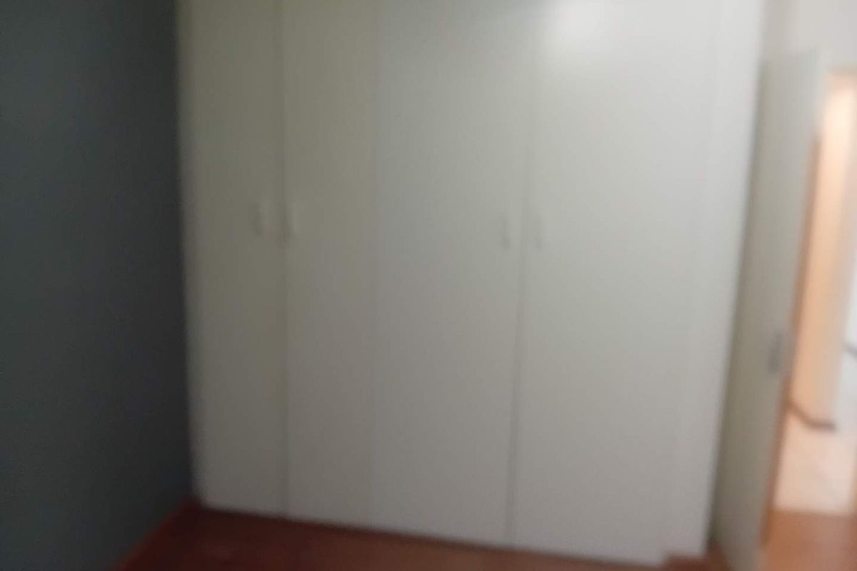 A bedroom featuring built-in cupboards and laminate flooring.
