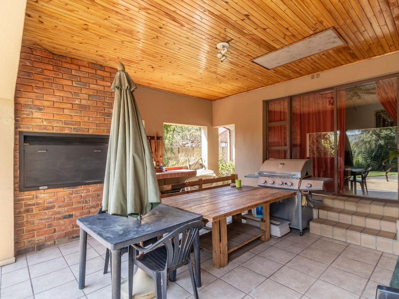 Covered patio area featuring a built-in braai, timber-clad ceiling, and tiled flooring, providing a functional outdoor entertainment space with direct access to the home.