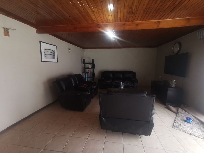 A spacious living room featuring ceramic floor tiles and a warm timber tongue and groove ceiling, providing a cozy and traditional atmosphere.