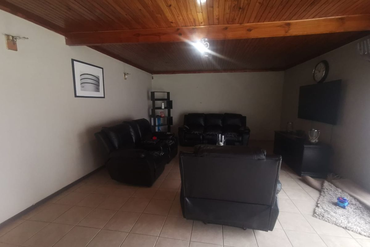A spacious living room featuring ceramic floor tiles and a warm timber tongue and groove ceiling, providing a cozy and traditional atmosphere.