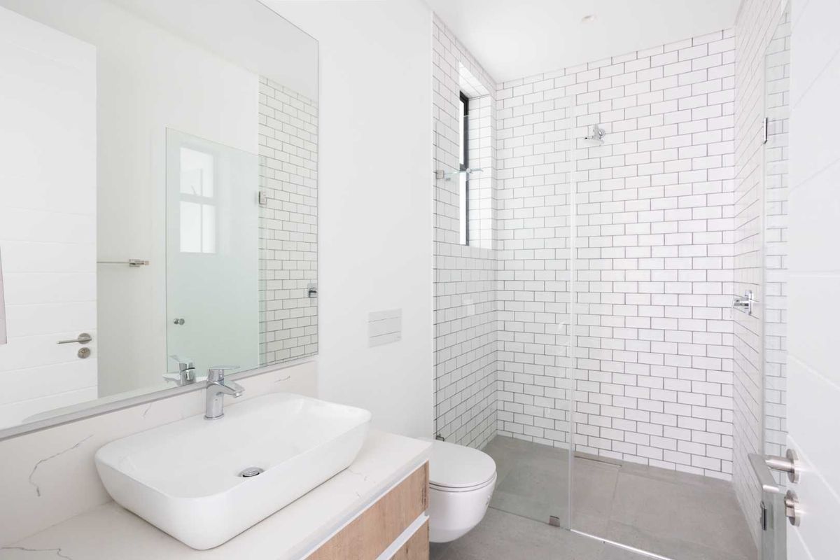 Modern bathroom featuring a walk-in shower with white subway tiles, a wall-mounted toilet, and a sleek vanity with a vessel sink.